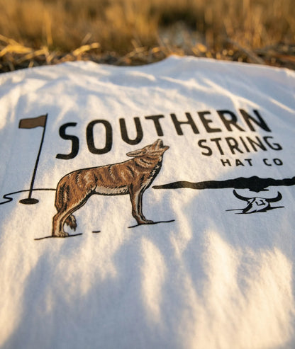 A close up macro shot of the back print of Southern String Hat Co's 'The Yote' drop t-shirt featuring a coyote and golf pin illustration on a white premium cotton tee